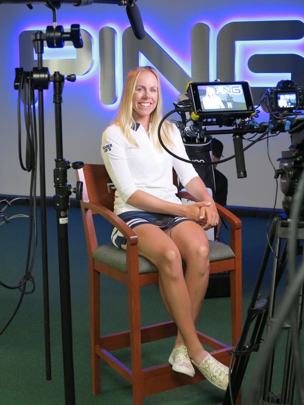 Pernilla Lindberg seated on a tall director’s chair in a studio, smiling