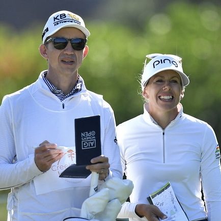 Daniel Taylor in caddie whites and Pernilla Lindberg laughing together on the course