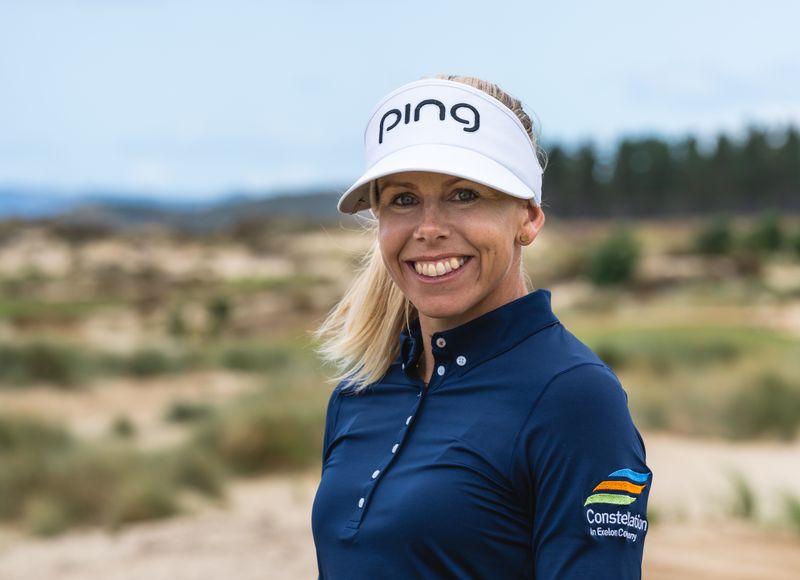 Portrait of Pernilla Lindberg smiling, wearing a white visor and navy top